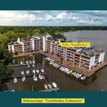 Wohnanlage Yachthafen Eyhausen mit Bootsanlegern und Wohnungen an Wasser.