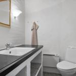 Badezimmer mit Waschbecken, Spiegel, Toilette und Handtuch.