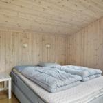 Schlafzimmer mit Holzwand, Bett und Fenster zur grünen Umgebung.