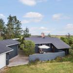 Moderne Villa mit Terrasse, Grill und Garten. Umgeben von Bäumen und Gras.