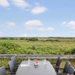 Terrasse mit Tisch und Stühlen bietet Blick auf grüne Landschaft und Horizont.