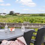 Terrasse mit Tisch, Stühlen und Blick auf Grünland und Häuser.