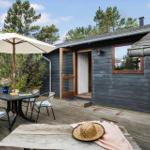 Terrasse mit Tisch, Stühlen und Sonnenschirm vor einem Haus mit dunklem Holzschindeldach.