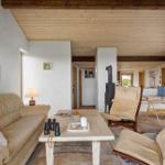 Wohnzimmer mit Sofa, Sesseln und Kaminofen. Holzdecke und Terrakottaboden.