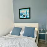 Schlafzimmer mit Bett, Wandbild und Nachttisch.