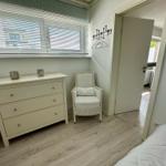 Schlafzimmer mit Schrank, Sessel und Blick auf angrenzenden Raum.