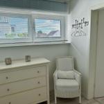 Schlafzimmer mit Schrank, Sessel und Fenster mit Jalousie.