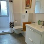 Badezimmer mit Dusche, Toilette und Waschbecken mit Spiegel.