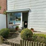 Hinterhof mit Tisch, Stühlen und Pflanzen. Durchgehende Glastür zum Innenraum.