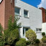 Modernes Haus mit weißen Fassaden, roten Ziegelsteinen und grüner Umgebung.