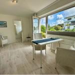 Essbereich mit Tisch und Stühlen. Große Fenster mit Blick auf Garten und Haus.