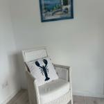 Weißer Rattan-Stuhl mit Kissen und Wandbild an der Wand.