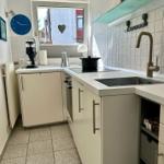 Küche mit weißen Schränken, Edelstahlspüle und Fenster mit Herz.