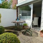 Hinterhof mit Tisch, Stühlen und Pflanzen. Durchgang ins Innere.