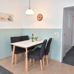 Essbereich mit Tisch, vier Stühlen und Wanduhr