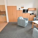 Wohnung mit Küche, Wohnbereich und TV. Möbel sind hell und funktional.