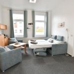 Zimmer mit Schlafcouch, Sitzgelegenheiten und Fenstern mit Blick.