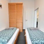 Zwei Einzelbetten mit gemusterten Bettwäsche und Holzschrank.