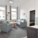 Wohnzimmer mit Sofa, Sesseln und Essbereich. Blick auf Schlafzimmer.