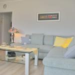 Wohnzimmer mit grauem Sofa, Glas-Tisch und Stehlampe.