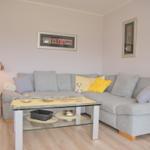 Ein Wohnzimmer mit grauem Sofa, Glas-Tisch und Stehlampe.