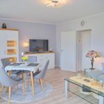 Wohn- und Essbereich mit Sofa, Esstisch und Fernseher.