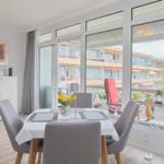 Esszimmer mit Tisch, Stühlen und Blick auf Balkon mit Sitzgelegenheiten.