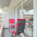 Terrasse mit Tisch, zwei roten Stühlen und Blick auf Wohnbereich.