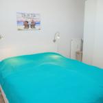 Schlafzimmer mit Bett, Nachttisch und Kleiderschrank. Wandbild und Stehlampe.