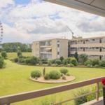 Balkon mit Blick auf Grünfläche, Gebäude und Riesenrad.