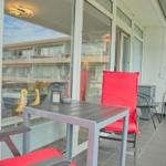 Terrasse mit Tisch, zwei roten Stühlen und Blick auf Gebäude.