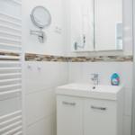 Badezimmer mit Waschbecken, Spiegel und Heizkörper.