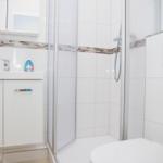 Badezimmer mit Dusche, Waschbecken und Toilette.