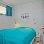 Schlafzimmer mit Bett, Nachttisch und Wandbild.