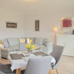 Wohn- und Essbereich mit Sofa, Esstisch und Wandbildern.