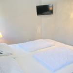 Schlafzimmer mit Bett, Lampe und Wandfernseher.