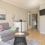 Wohnzimmer mit Sofa, Couchtisch und Fernseher an der Wand.