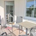 Terrasse mit Tisch und Stühlen, Schiebetür und Fenster zur Wohnung.