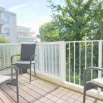 Terrasse mit Gartenmöbeln und Blick auf Bäume und Gebäude
