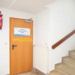 Trockner, Waschmaschine und Billard hinter Tür. Treppenhaus mit Holzgeländer.