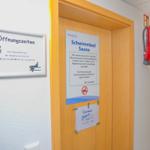 Türe zum Schwimmbad und Sauna mit Öffnungszeiten und Sicherheitsausrüstung.