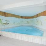 Innenpool mit Meeresmotiven an den Wänden und Holzwandverkleidung.