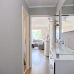 Flur mit Spiegelschrank und Blick in Wohnzimmer mit Sofa und Fenster.