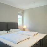 Zimmer mit Doppelbett, Fenster und Wandfernseher.