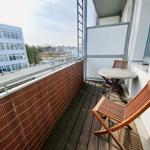 Terrasse mit Tisch, zwei Stühlen und Blick auf Gebäude.