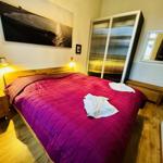 Schlafzimmer mit Doppelbett, Holzmöbeln und Wandbild.