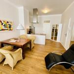 Essbereich mit Tisch und Stühlen, Küche und schwarzer Ledersessel