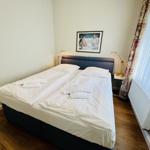 Schlafzimmer mit Doppelbett, Bild an der Wand und Fenster mit Vorhängen.