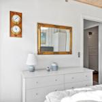 Schlafzimmer mit weißem Schrank, Spiegel und Wanduhr