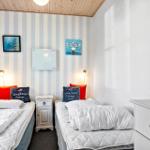 Zwei Betten mit weißen Bettwäschen, gestreifter Wand und Modellboot.